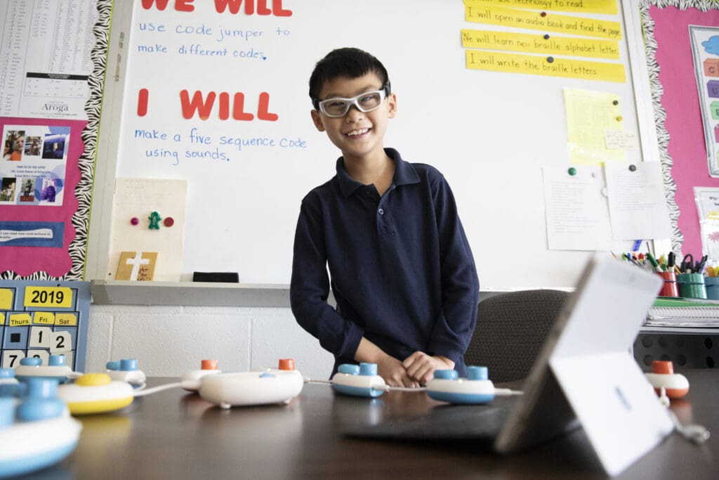 Smiling boy with Code Jumper device and laptop
