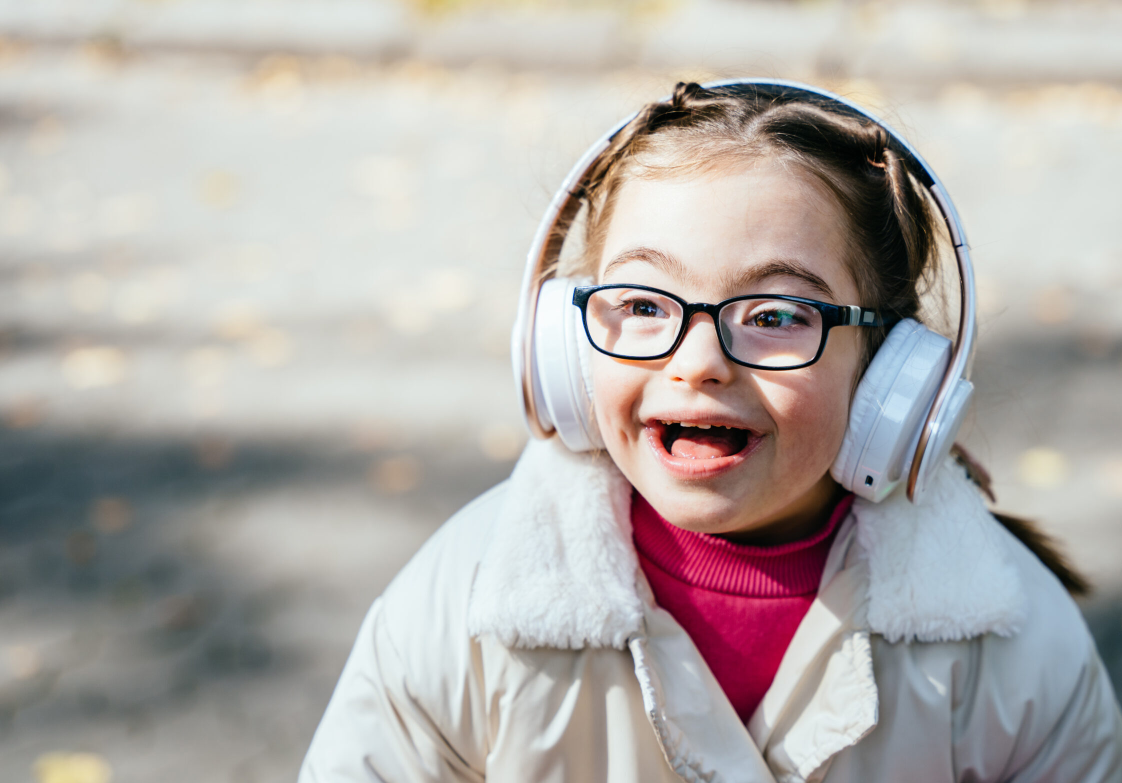 A girl wearing headphones and glasses, smiling.