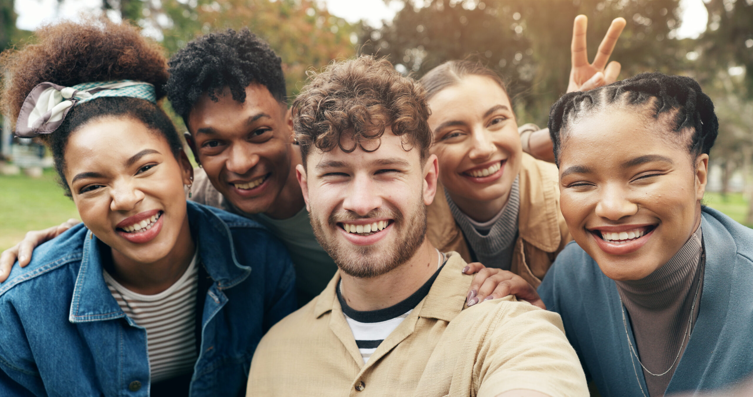 Two men and three women huddled close together and smiling at the camera.