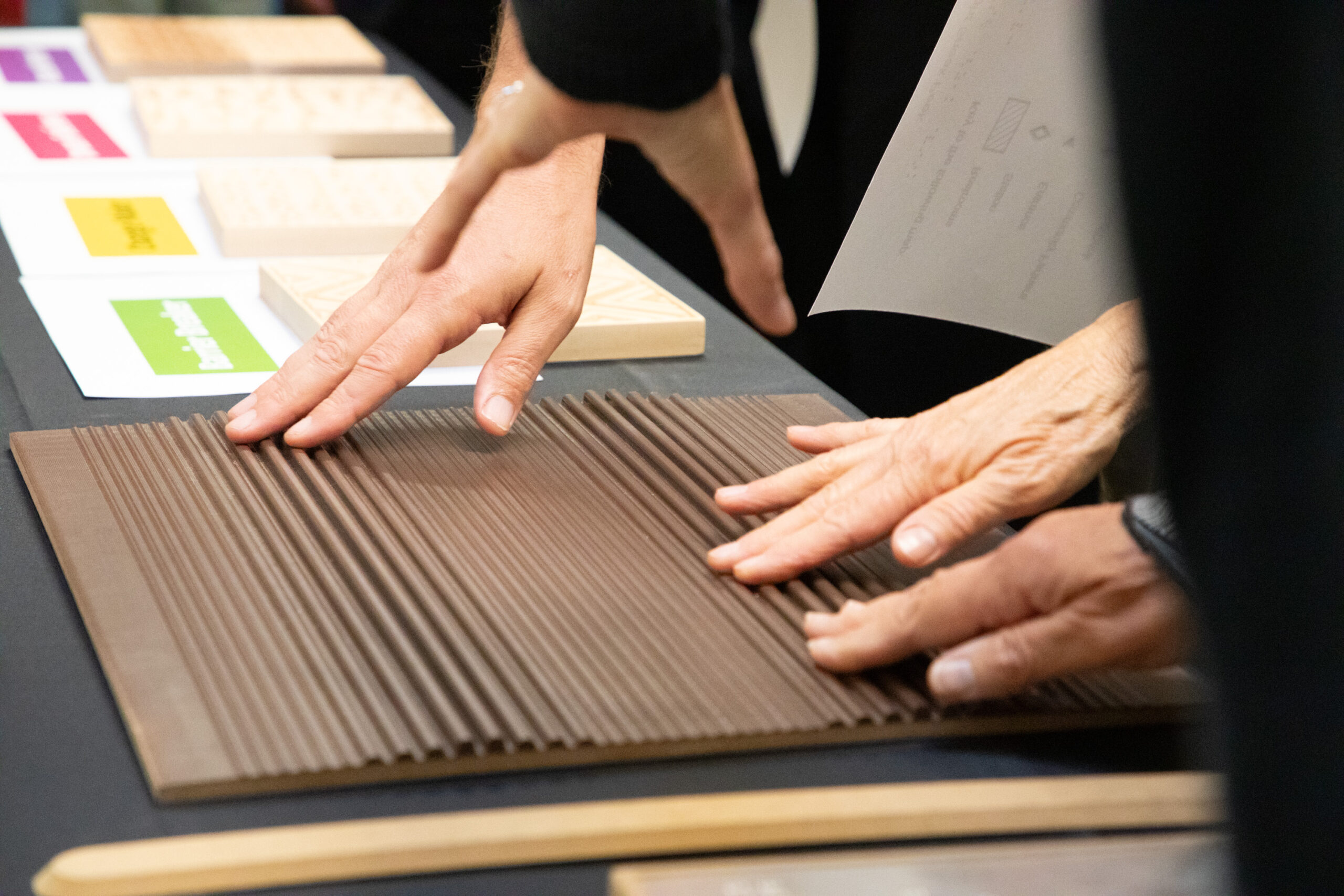 Hands touching a brown material with raised textured stripes of various sizes.