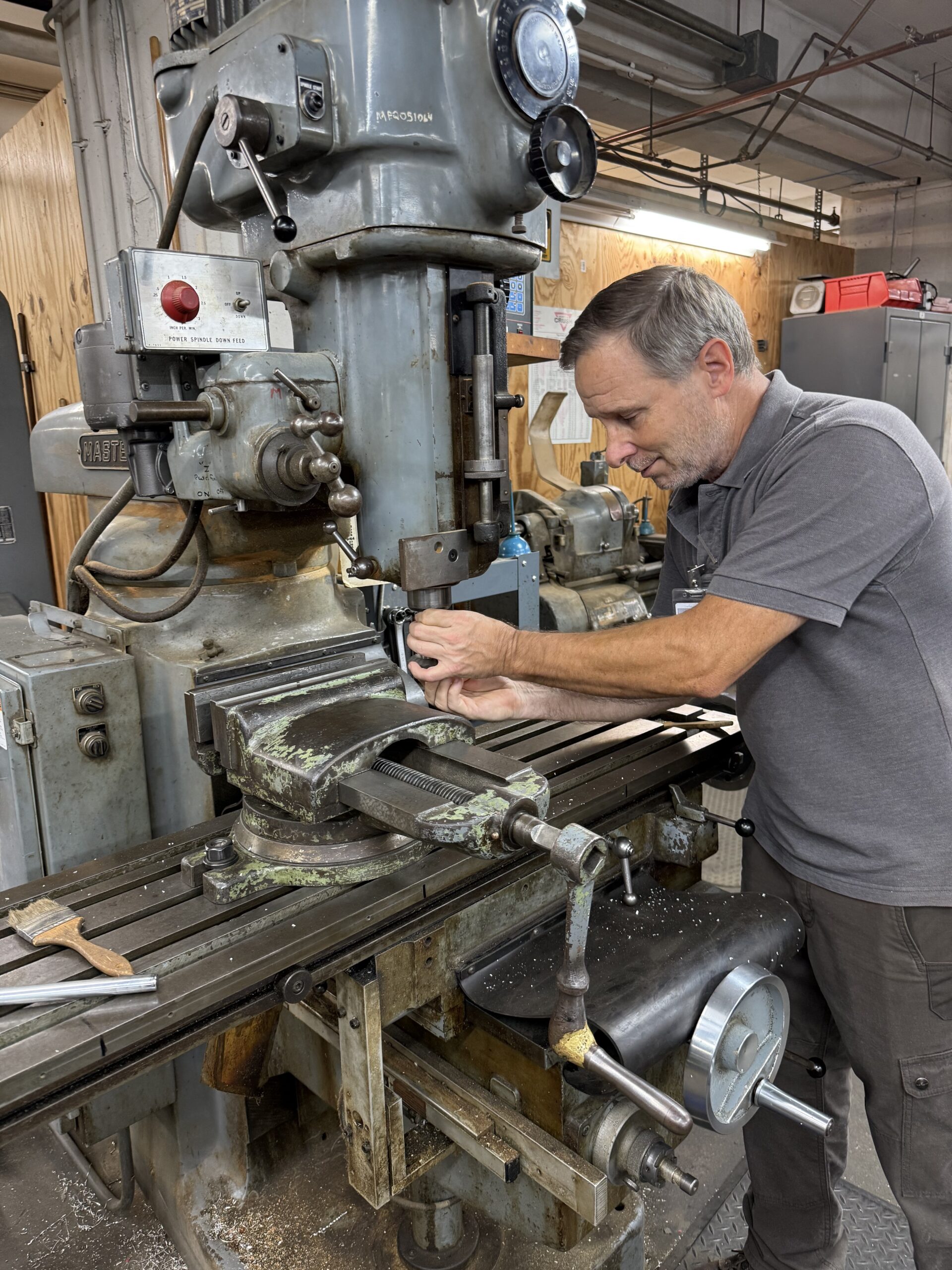 Man in a grey shirt using a large piece of machinery