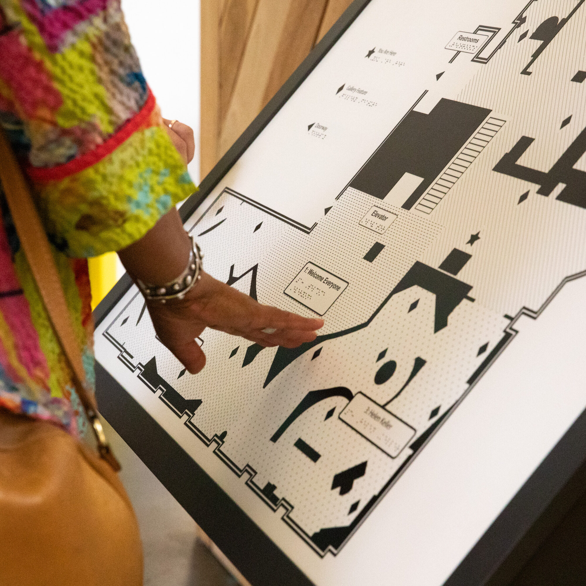 Person in a colorful jacket touching a tactile map of the museum.