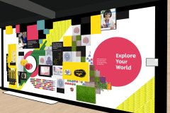 Facing north, the visitor faces a large white wall at the gallery edge, adorned with a dynamic collage. This collage is a vibrant mix of accessible educational tools, brand colors, shapes, portraits, drawings, textures, and even a section of grass. The components of the collage, predominantly square in shape with some circular elements, are artfully layered over one another. Positioned on the far right of the wall is a prominent APH pink dot, featuring the phrase Explore your World in white lettering. To the right of this pink dot, there is an accessible braille panel.